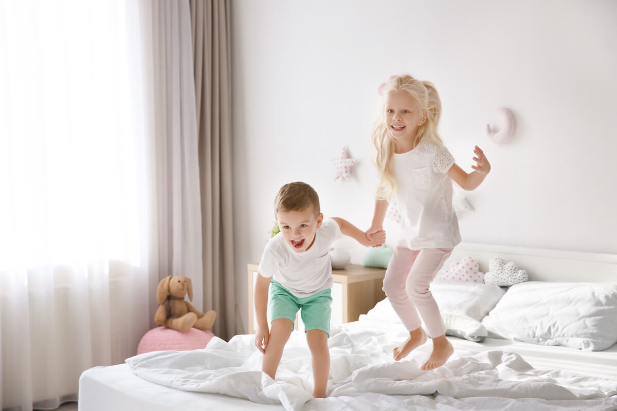 2 kids jumping on a bed