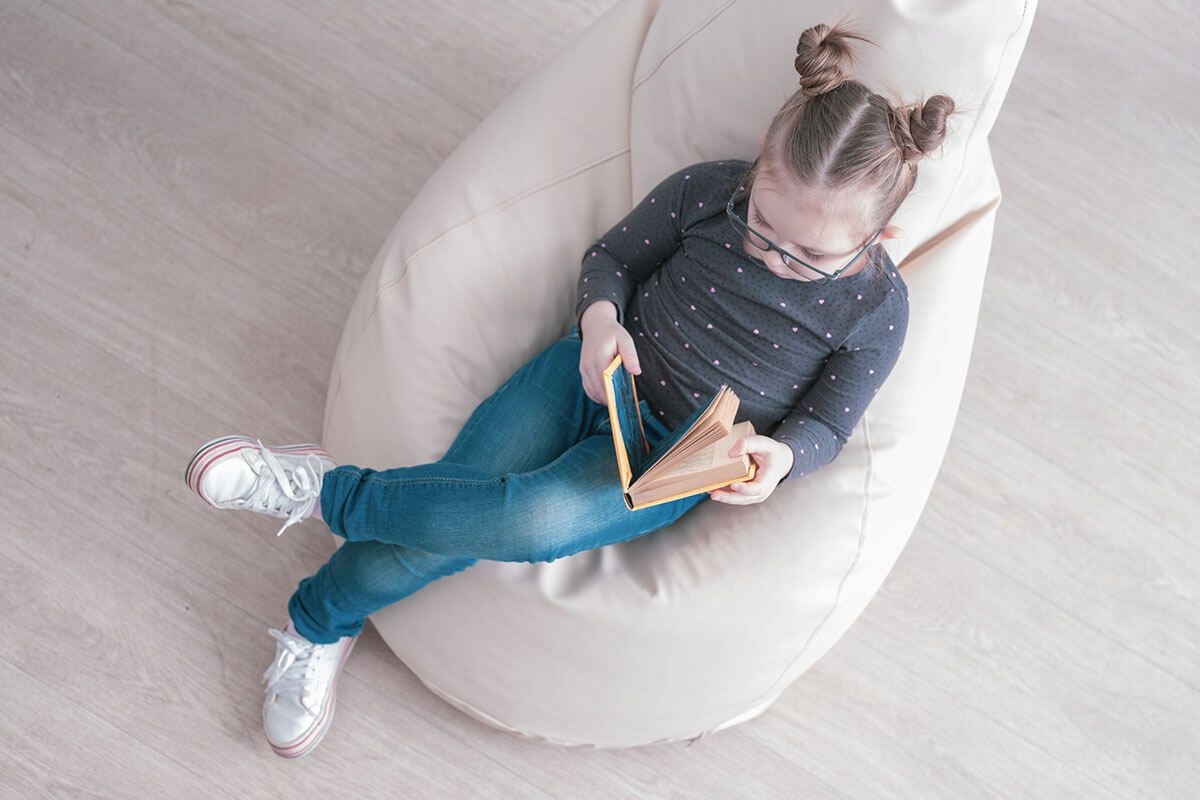 Girl reading a book while sitting on a bean bag