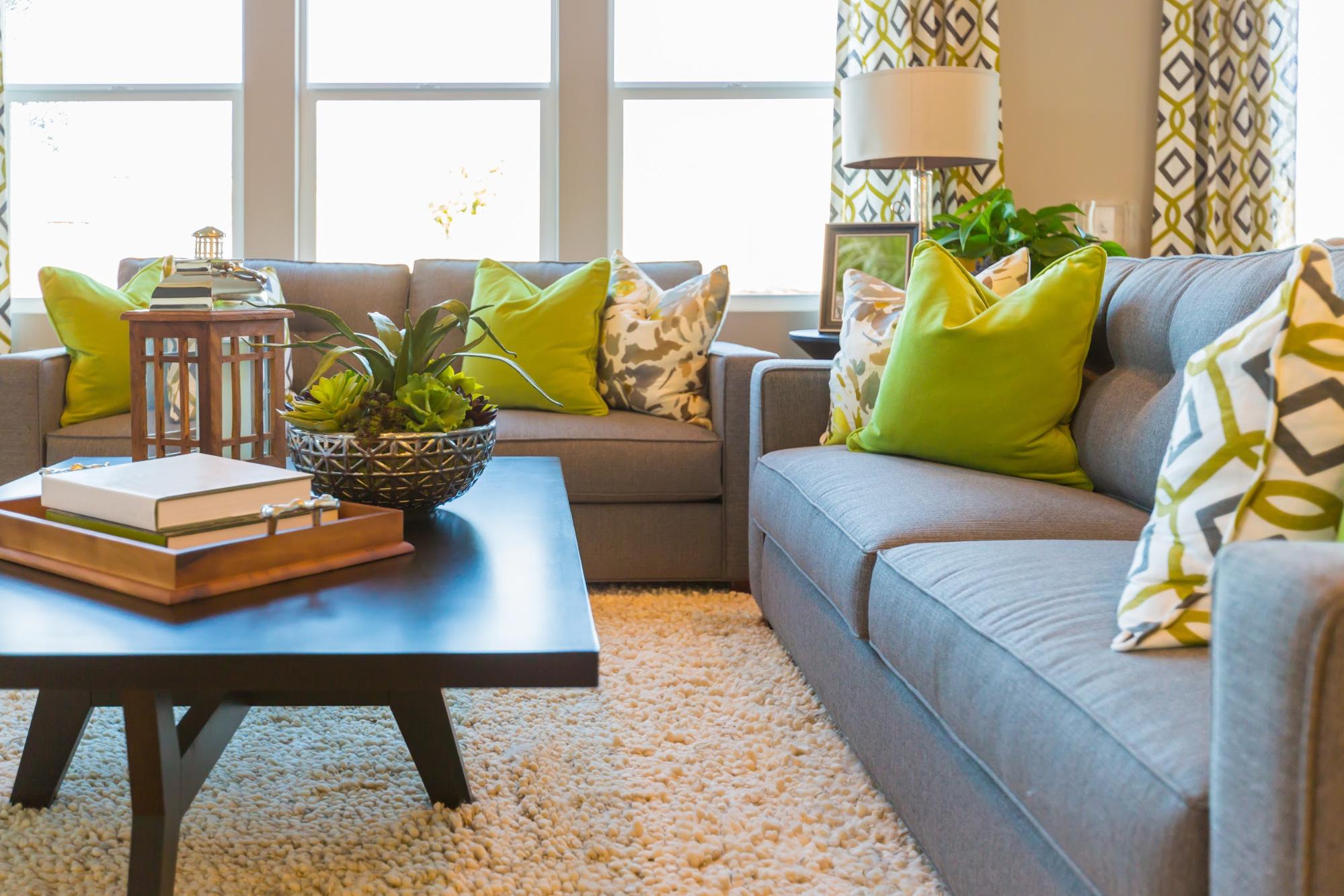 Living area with coffee table, couch and green accent throw pillows