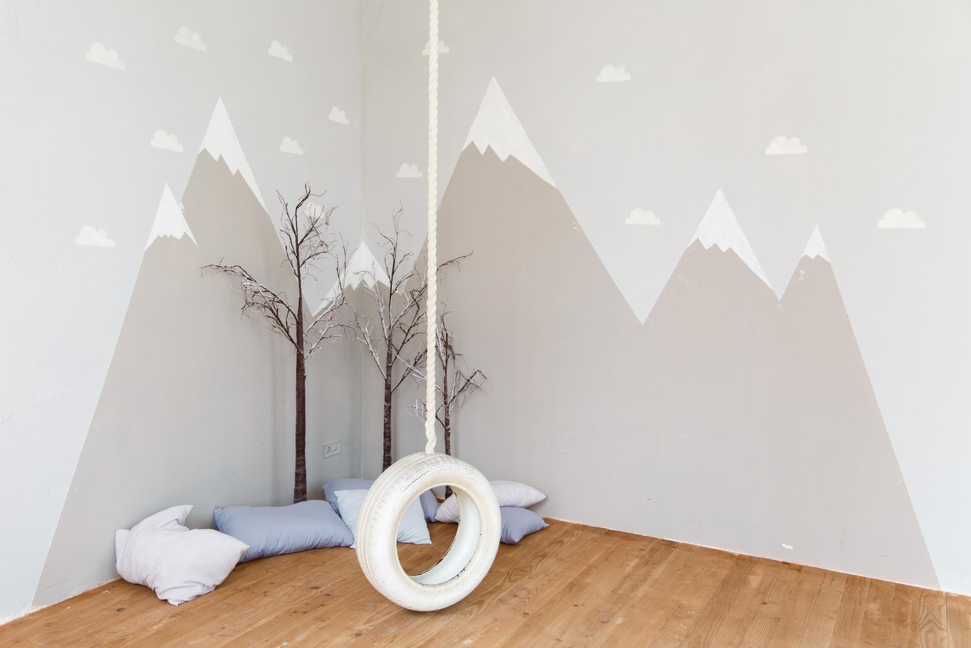 room with illustration of mountains and a swing hanging from the ceiling