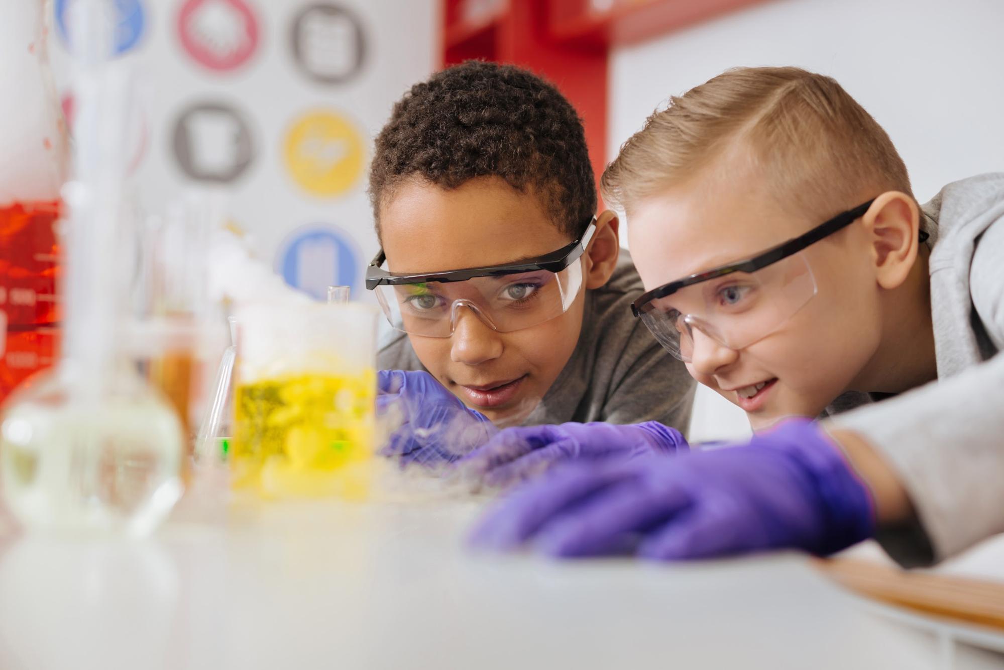 two kids wearing safety goggles while conducting an experiment