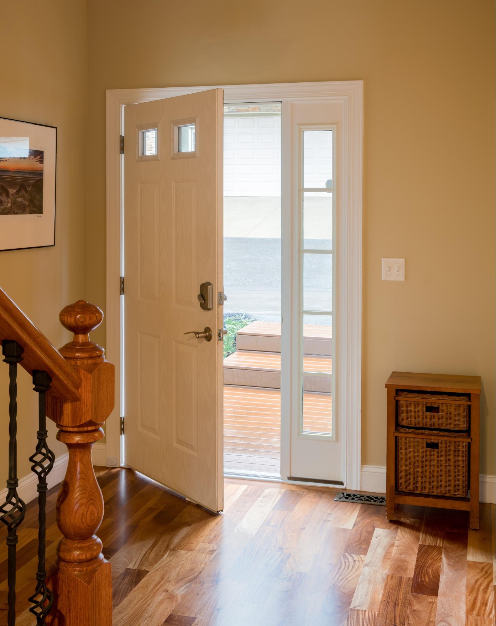 Open front door and an end table with storage beside it