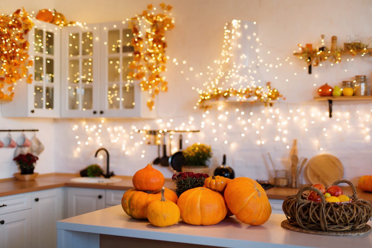 Pumpkins on a kitchen counter and Christmas lights on the wall