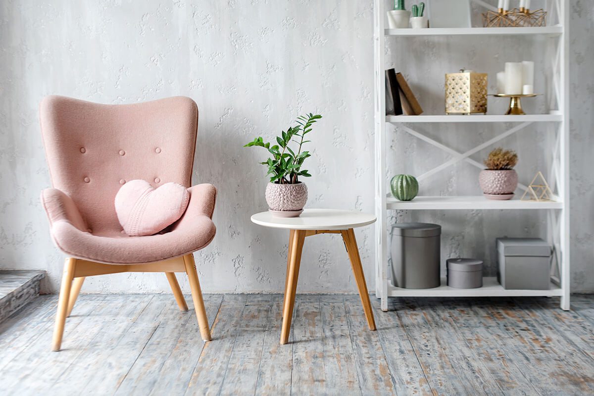 Heart shaped pillow on a pink armchair with a side table and white shelf